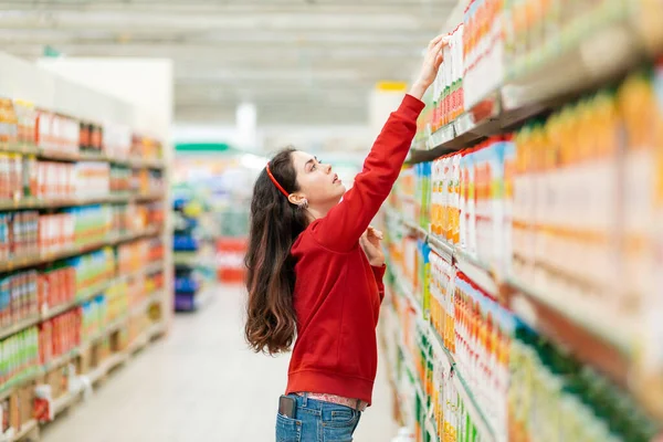 Una Giovane Donna Caucasica Con Maglione Rosso Cerca Succo Frutta — Foto Stock