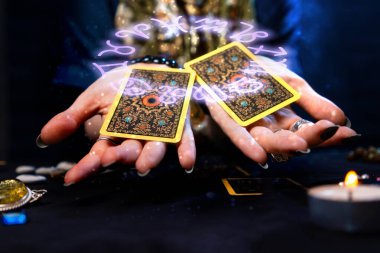 Haritacılık. Falcı avuçlarında iki Tarot kartı tutuyor. Zodyak çemberi, elimizin üstünde kartlarla tasvir edilir. Kehanet, astroloji ve ezoterizm kavramı..