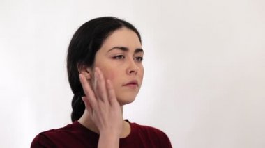 Elleriyle yanaklarında kızarıklık gösteren genç bir kadının portresi. Beyaz arka plan. Rosacea ve couperose konsepti