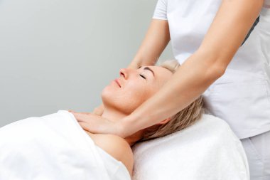 Profesyonel kozmetik uzmanı salondaki müşteriye yüz masajı yapıyor. Kaldırma ve güzellik prosedürleri kavramı.