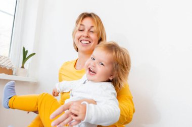 Genç bir anne küçük çocuğuyla oynuyor ve eğleniyor. Mutlu annelik kavramı.