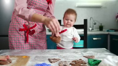 Gülümseyen bir bebeğin portresi annesine bakıyor ve hareketlerini tekrarlamaya çalışıyor. Annem hamuru dışarı atıyor. Çocuklarla evde yemek pişirmek.