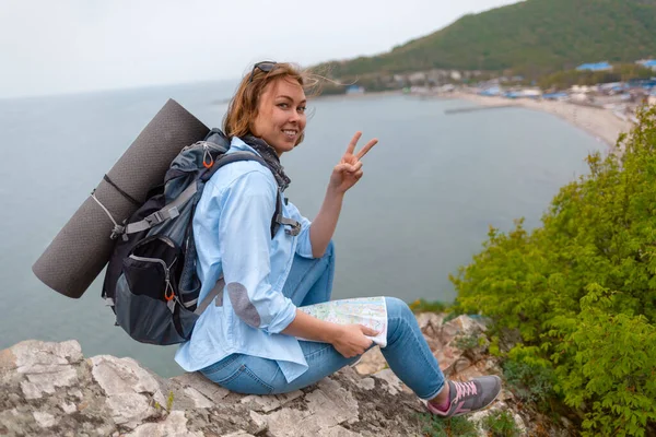 笑顔の女性観光客に座っている岩の棚に地図で彼の手とカメラのポーズ — ストック写真