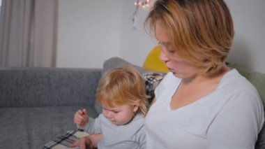 A woman is engaged in reading with a small autistic child. Pronunciation and speech therapy. Slow motion.
