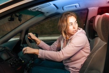 Sağ elini kullanan korkmuş genç beyaz bir kadının portresi. Polis siren ışığına bakıyor. Yol kazaları ve kovalamaca kavramları.