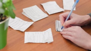 A woman keeps accounting, writing down expenses in a notebook. Hands close-up. Savings and investment