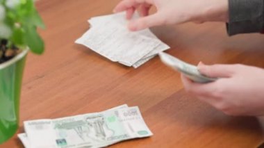 Female's hands puts money next to the checks. Close up. Savings and accounting