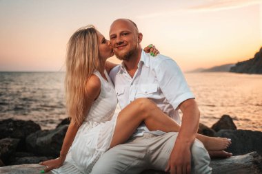 Valentines day. Pretty couple of young caucasians man and woman. In the background sunset and ocean. Romantic date.