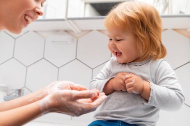 Child learning a hygienic routine. A happy little girl learns from a teacher how to wash her hands. Hygiene procedures.
