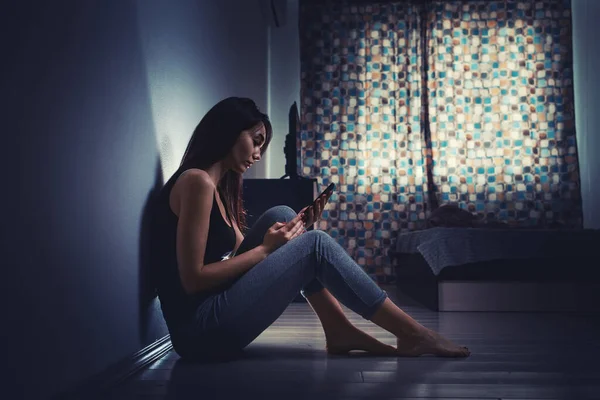 家庭内暴力の概念 排出された白人女性は暗い部屋の床に座って 壁に反対し スマートフォンを使用しています — ストック写真