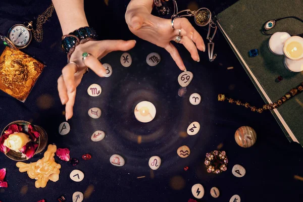 Falcı, rünlerle çevrili bir mum ve astrolojik bir çemberin parıltısını yaratır. Kehanet, astroloji ve geleceği tahmin etme kavramı..