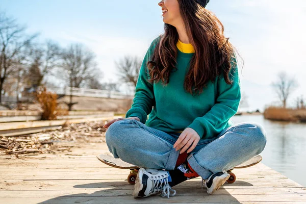 Young Caucasian Woman Sits Cross Legged Skateboard Looks Away Smile — Foto de Stock