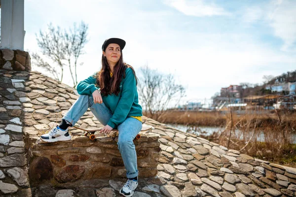 Young Smiling Beautiful Caucasian Woman Sits Skateboard Looks Away Background — ストック写真