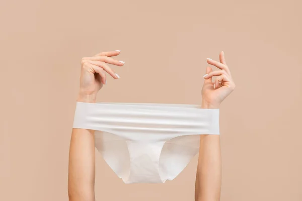Elegantní Ženské Ruce Kalhotkami Nataženými Přes Béžové Pozadí Rozumím Koncept — Stock fotografie