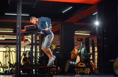 Sporcu adam spor salonunda ekipmanla antrenman yapıyor. Uzayı kopyala Dips. Zindelik ve refah kavramı.