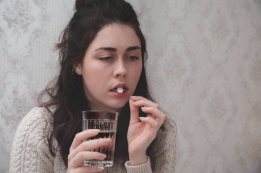 Hasta kız bir bardak suyla ilaç alıyor..