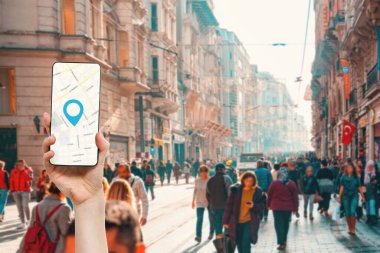 Çevrimiçi harita uygulaması olan akıllı telefonu tutan bir el. Arka planda, insanlarla dolu bir şehir caddesi. Seyahat ve seyrüsefer uygulamaları kavramı.