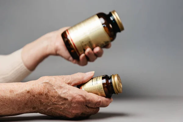 Feche Mãos Mulher Sênior Que Mantém Dois Jarros Medicina Fundo — Fotografia de Stock