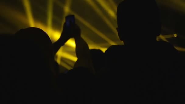 人们在音乐会上 一个男人用智能手机记录了乐队的表演 俱乐部的气氛中闪烁着黄蓝色的光芒后视镜娱乐的概念 — 图库视频影像