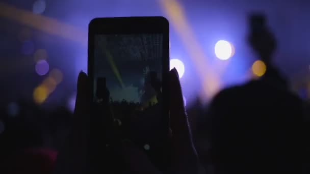 人们在音乐会上 一个女人的手与智能手机记录了一个视频乐队的表演 靠近点俱乐部的气氛 紫色的光芒 娱乐的概念 — 图库视频影像