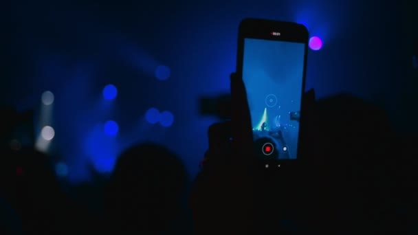 人们在音乐会上 一个男人的手与智能手机记录了一个视频乐队的表演 靠近点俱乐部的气氛 紫色的光芒 娱乐的概念 — 图库视频影像