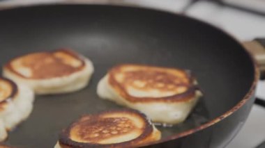 Altın krepler kızgın tavada yağda kızartılır. Yakın plan. Yakınlaştır. Kahvaltıda krep pişiriyorum..