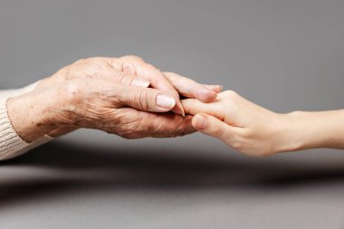 Yaşlı bir kadın kızının elini avuçlarında tutuyor. Yakın plan. Aile kavramı ve akrabalarla ilgilenmek.