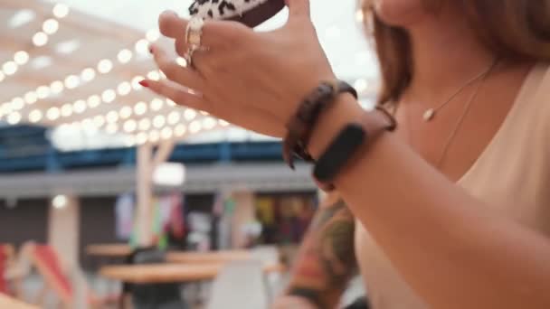 一个晒黑了的漂亮女人在阳台上的咖啡店里高兴地吃着甜甜圈 框架从桌子到女人脸上的运动 — 图库视频影像