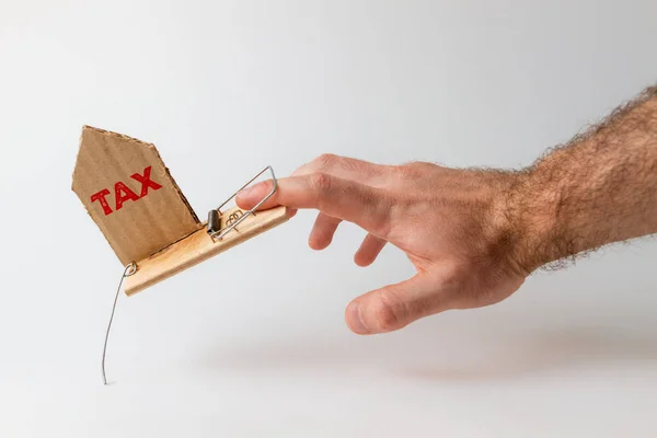 银行投资和风险的概念 一个人的手掉进了一个捕鼠器 上面插了一块纸板 上面写着Tax — 图库照片
