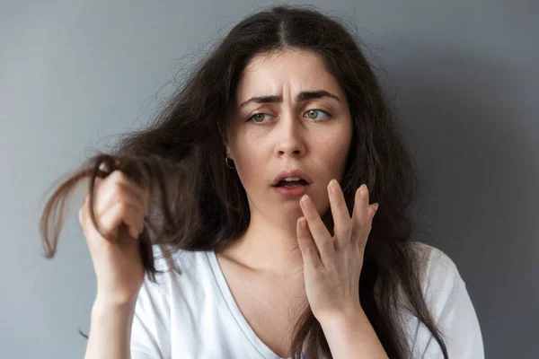 Young Caucasian Frustrated Woman Looks Tips Her Long Dark Hair — Stock Photo, Image