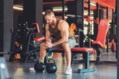 Atletik sakallı adam spor salonunda çıngıraklı yılanlarla antrenman yapıyor. Fitness ve vücut geliştirme konsepti.
