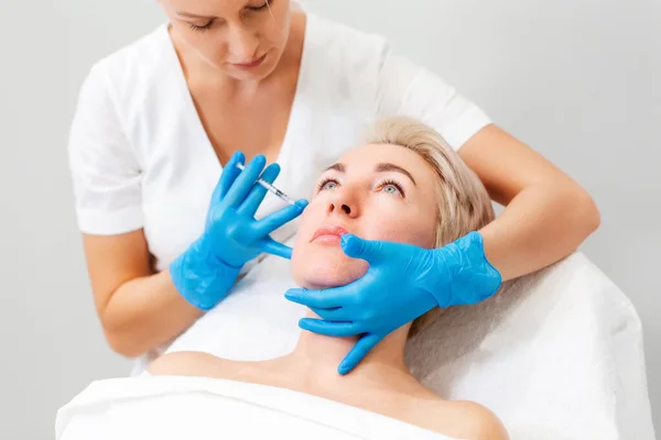 Dorosła Blondynka Wizycie Kosmetologa Kosmetolog Niebieskich Rękawiczkach Medycznych Wkłada Wypełniacz — Zdjęcie stockowe