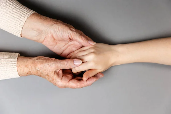 Avó Está Segurar Mão Neta Mãos Vista Deitado Fundo Cinzento — Fotografia de Stock