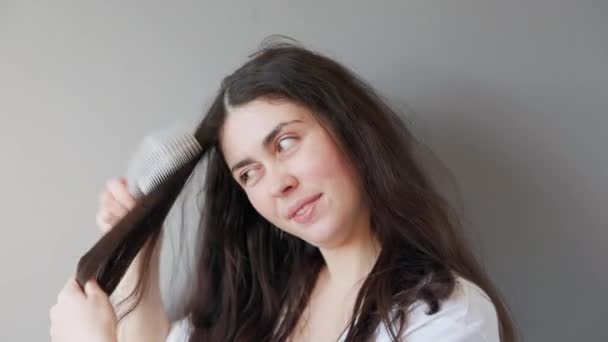 若い白人女性の肖像画で 髪の毛が絡まり合っている 灰色の背景 ヘアケアの概念 — ストック動画
