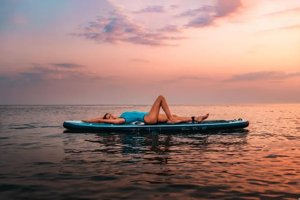 一个穿着泳衣的年轻而性感的高加索女人躺在了跳板上 夕阳西下复制空间 水上运动和夏季活动的概念 — 图库照片