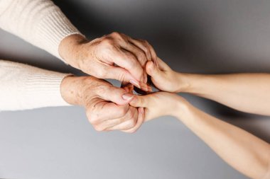 Close up of females hands of young and senior women. Flat lay. The concept of International Day of Older Persons.
