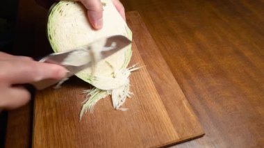 Mutfak masasındaki ahşap kesme tahtasının üzerinde lahana kafasının bir kısmının parçalanması.