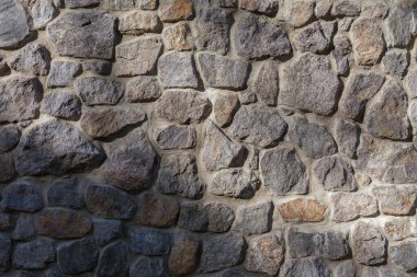 Duvarın bir kısmı doğal gri taşlarla çevrili. Farklı boyutlarda, kısmen gölgede. Arkaplan, doku,