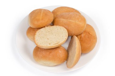 Küçük yuvarlak yuvarlak çörekler ve beyaz arka plandaki beyaz tabakta yatay kesilmiş bir çörek yığını.