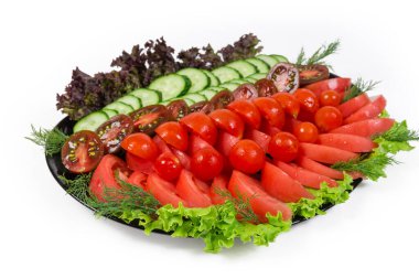 Taze domatesli sebze salatası yeşil ve kırmızı salatalıklı salatalık beyaz arka plandaki büyük siyah salatada, seçici odak noktasında yakın plan 