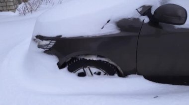 Otoparkta karla kaplı bir araba parçası.