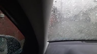 Arabanın ön camında yağmur damlaları vardı.