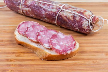 Buğday ekmeğinden yapılmış açık sandviç ve sosis dilimleri bambu kesme tahtasındaki aynı sosise karşı, yakın plan.