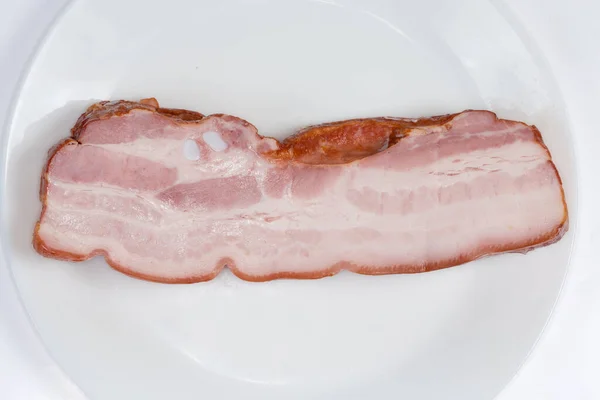 白い背景に白い皿の上に小さな肋骨を持つ皮膚の上に煮た豚肉の腹のピース トップビューのクローズアップ — ストック写真