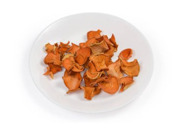 Beyaz arka plandaki beyaz tabakta kurumuş ince elma dilimleri.