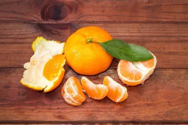 Yaprak, segmentler ve kabuğu soyulmuş mandalinayla dolu taze bir mandalina eski kırsal masa, üst manzara.