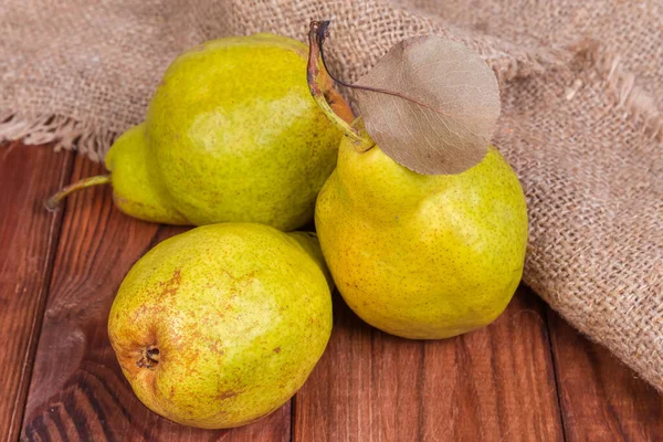 Olgun armutlar kuru yaprak ile eski kırsal masa üzerinde çuval bezi karşı, yakın çekim