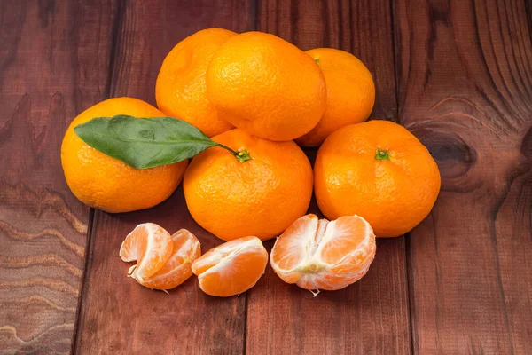 Küçük bir yığın taze mandalina ve kabuğu soyulmuş mandalina parçaları eski kırsal masada.
