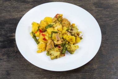 Etli haşlanmış sebze porsiyonu, ayrıca siyah bir yüzey üzerinde beyaz bir tabakta ragout olarak da bilinir.