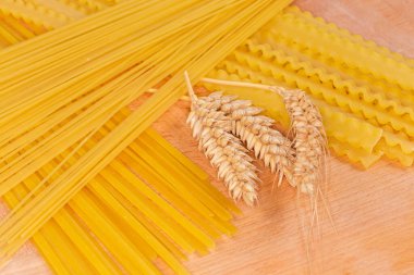 Tahta bir tahtanın üzerinde buğday kulaklı farklı türde hamur işi, seçici odak noktasında yakın plan.